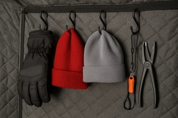 Winter jackets and rods hanging from hooks on a shelter wall