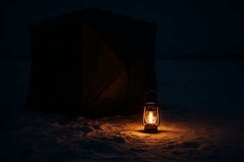 Lantern glowing inside a dark shelter during a noisy night
