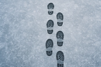 Boot prints running in a straight line across fresh snow