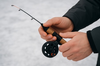 Hands holding an ice auger handle from the front with tape marks