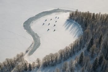 Snowy ice bay seen from above with faint tracks and shelters