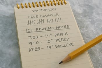 Notebook and hole counter resting on drilled ice next to a boot